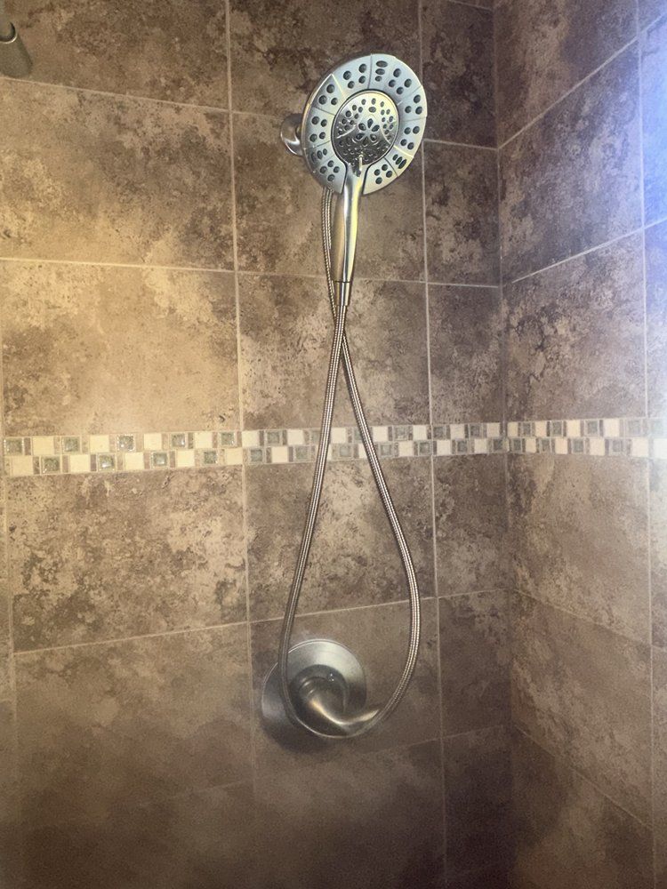 Shower head with a handheld wand in a tiled shower.