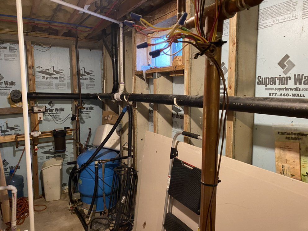 Basement with blue water tank, pipes, wires, and insulation on the walls.