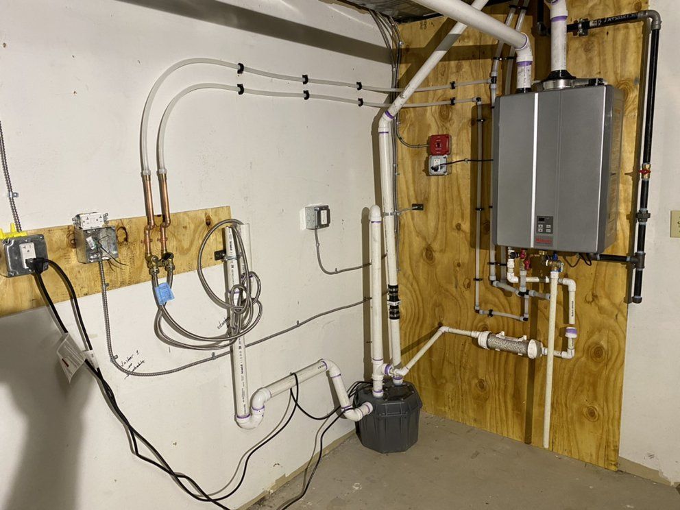A utility room with water heater, pipes, and electrical components mounted on a wooden wall.