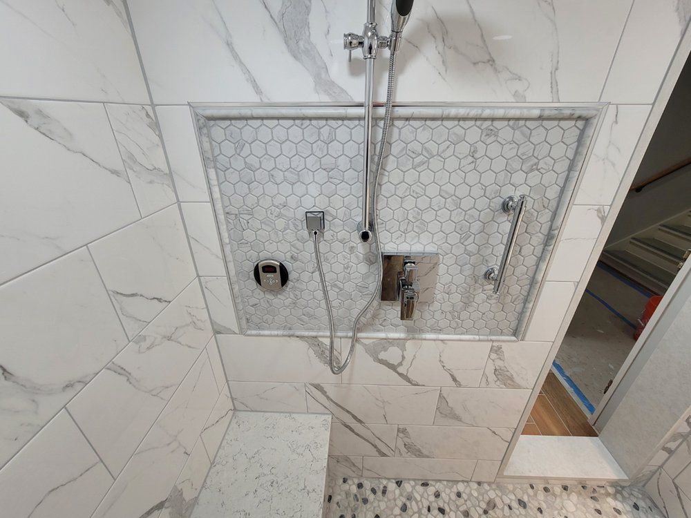 Modern shower with white marble walls, mosaic tile accent, and chrome fixtures.