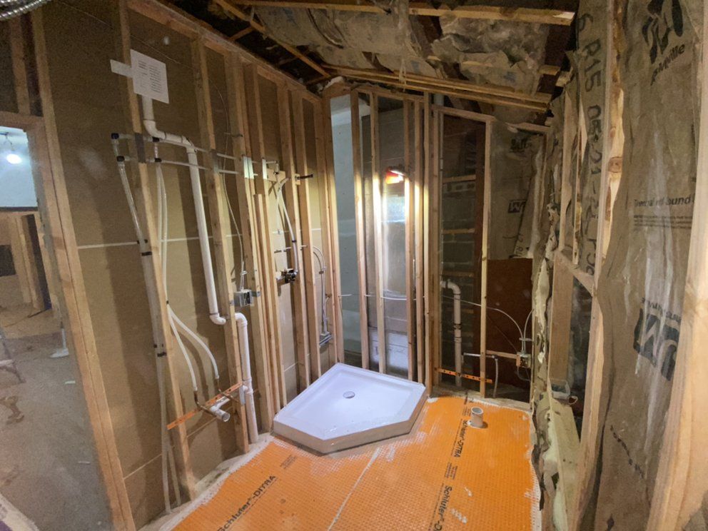 Bathroom under construction: Framing, plumbing, shower pan visible. Insulation and orange subfloor present.