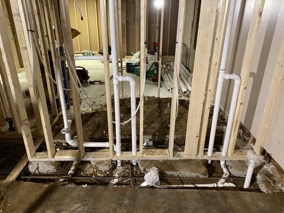 Interior view of construction site with plumbing pipes installed within wooden framing.