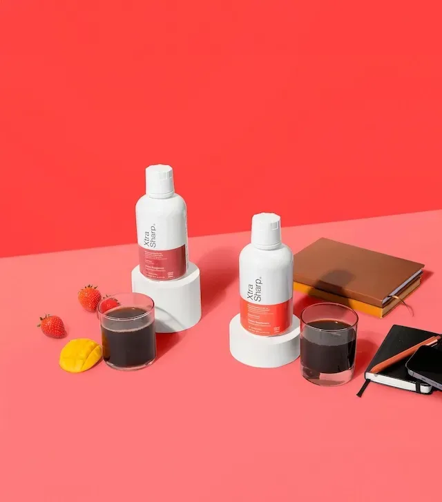 Botella blanca de suplemento líquido “Xtra Sharp” con banda roja; suplemento dietético.