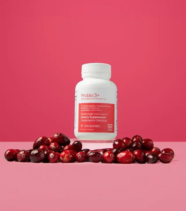 Botella blanca de suplemento Probio 3+ con arándanos sobre fondo rosa.