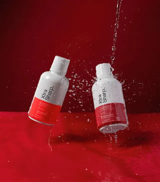 Botella de suplemento dietético líquido “Xtra Sharp”, etiqueta blanca y roja.