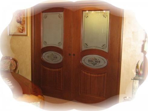 Una coppia di porte di legno con vetri incisi in una stanza.