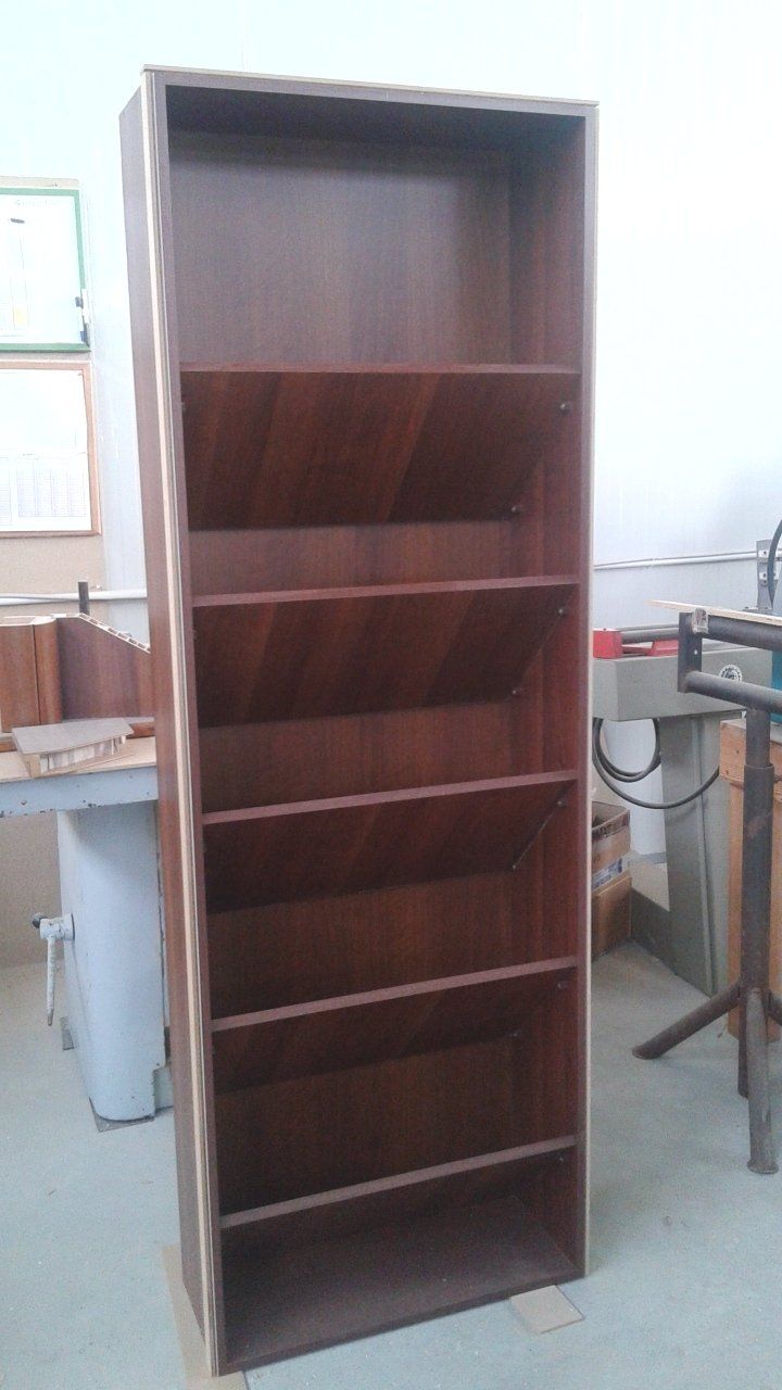 In una stanza c'è una libreria di legno vuota accanto a una macchina.