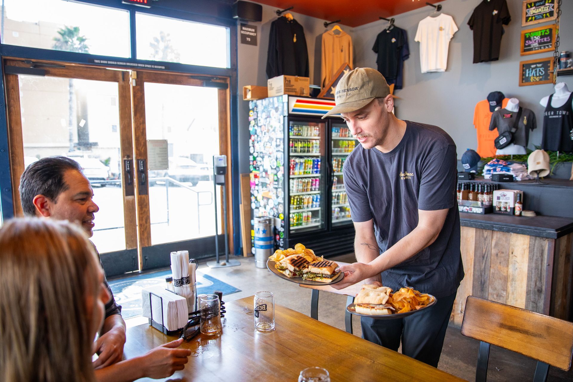 A man is serving food to a group of people at a table in a restaurant.