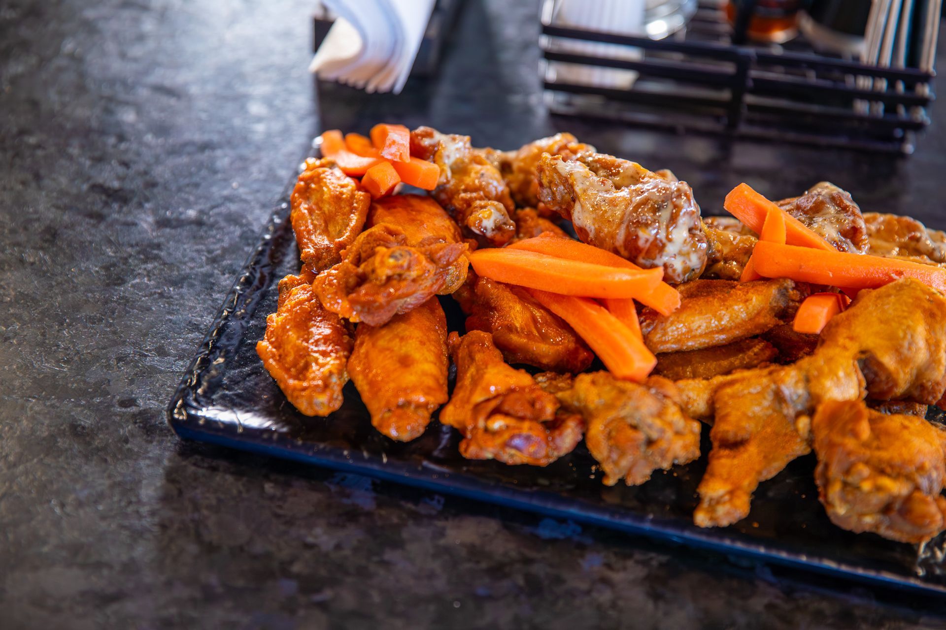 A plate of chicken wings and carrots on a table.