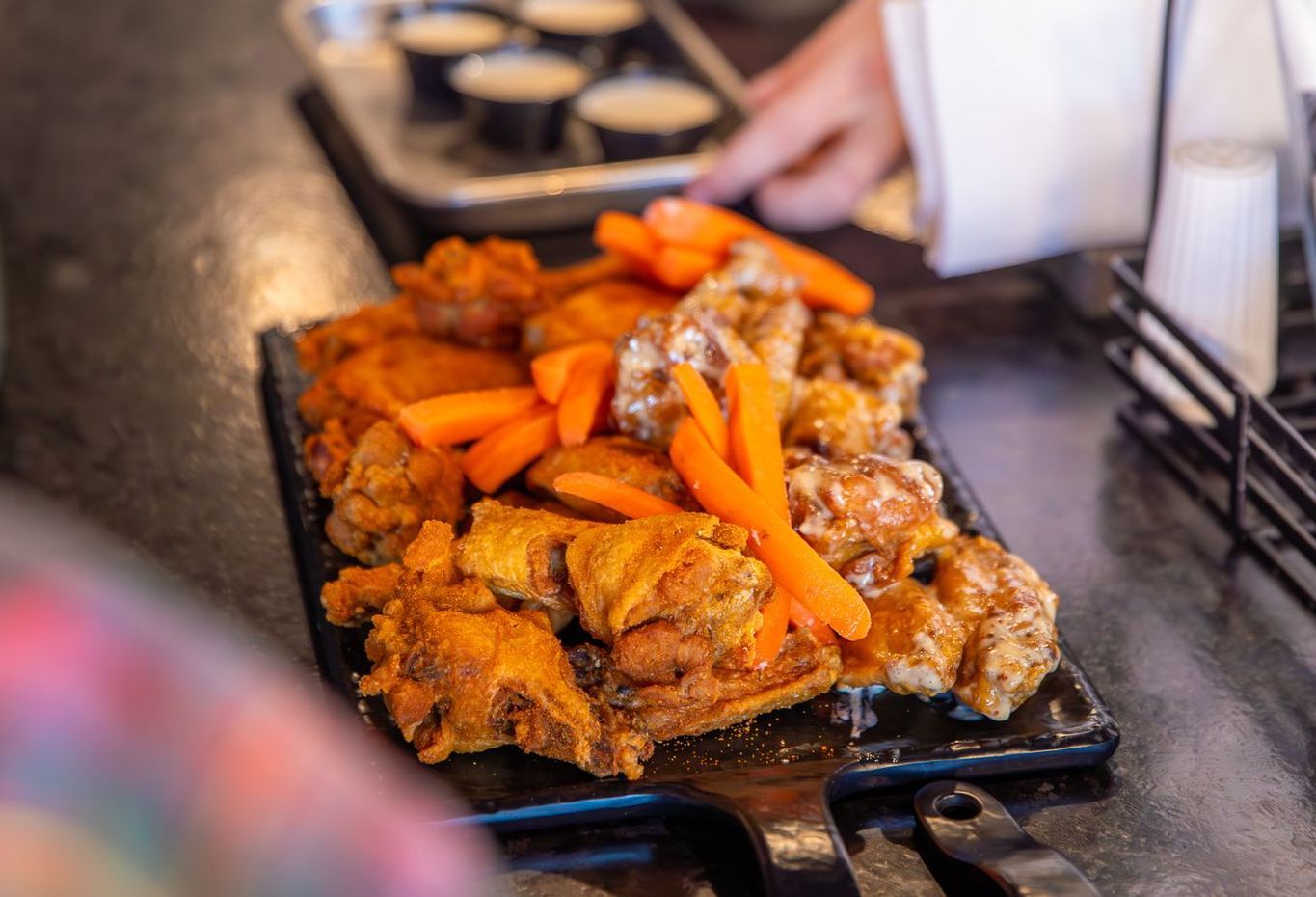 A plate of chicken wings and carrots on a table.