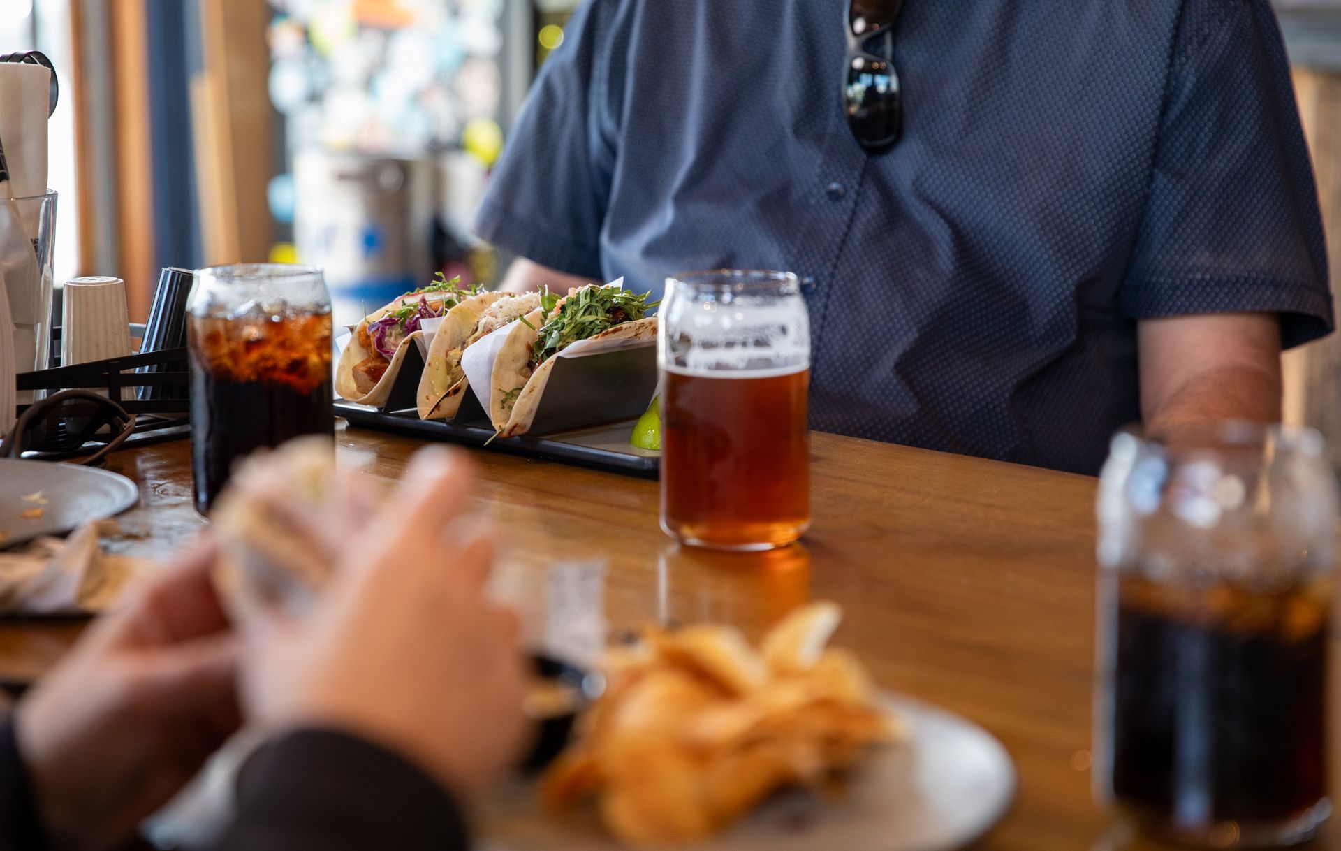 A group of people are sitting at a table eating food and drinking beer.