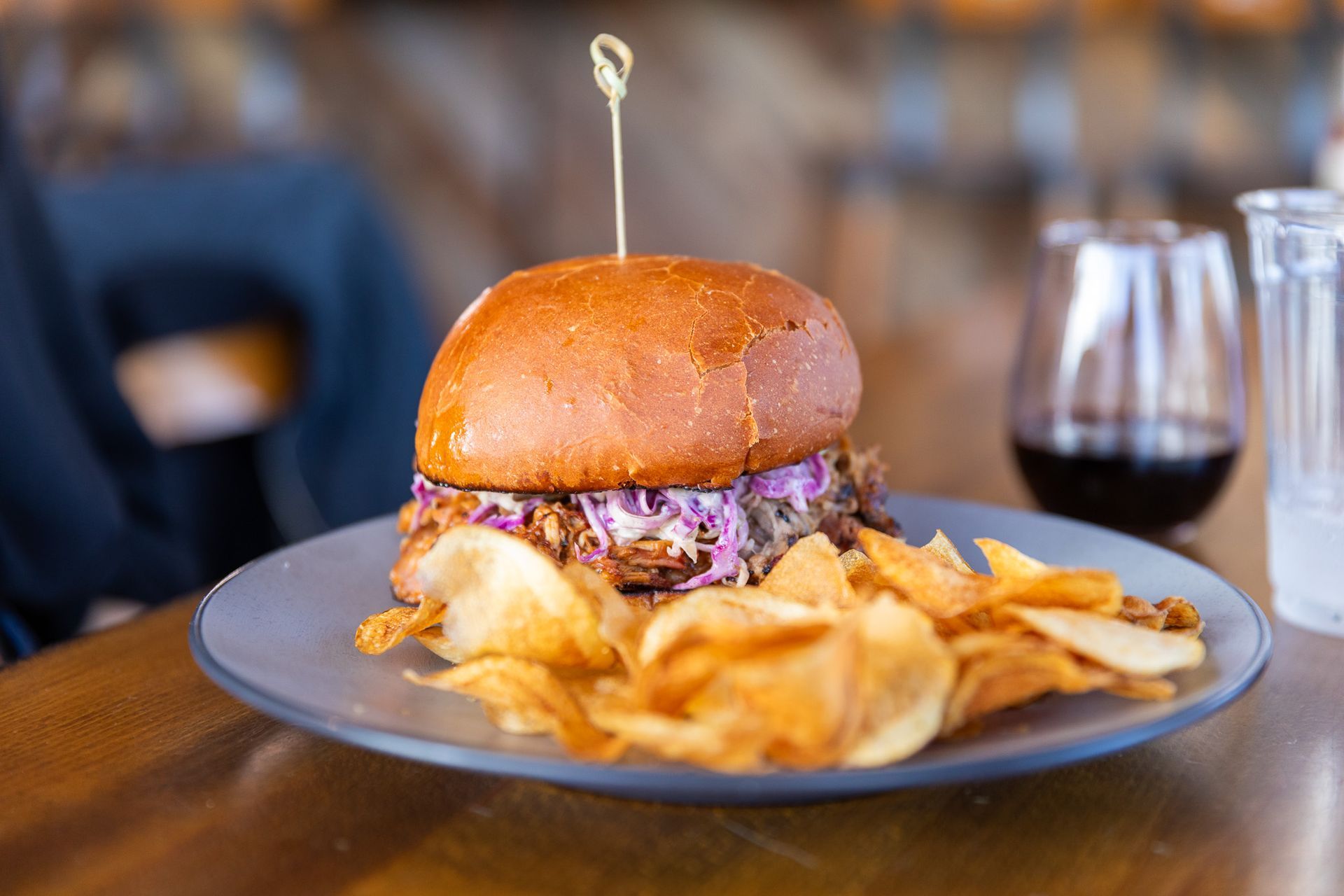 A pulled pork sandwich with coleslaw and chips on a plate.
