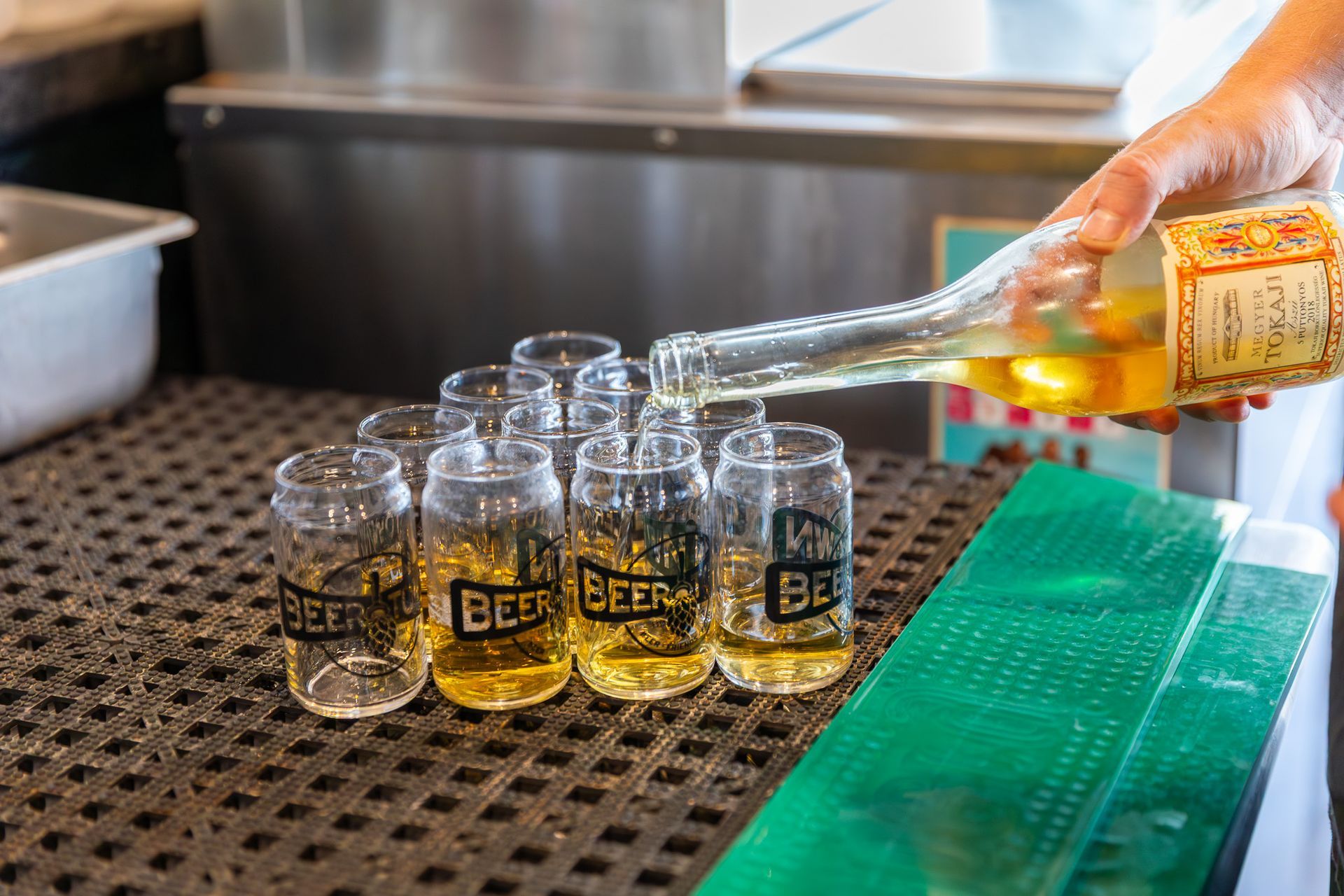 A person is pouring beer into shot glasses on a counter.