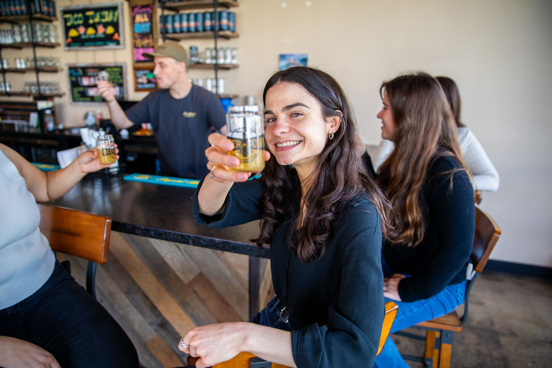 A woman is sitting at a bar holding a beer glass.