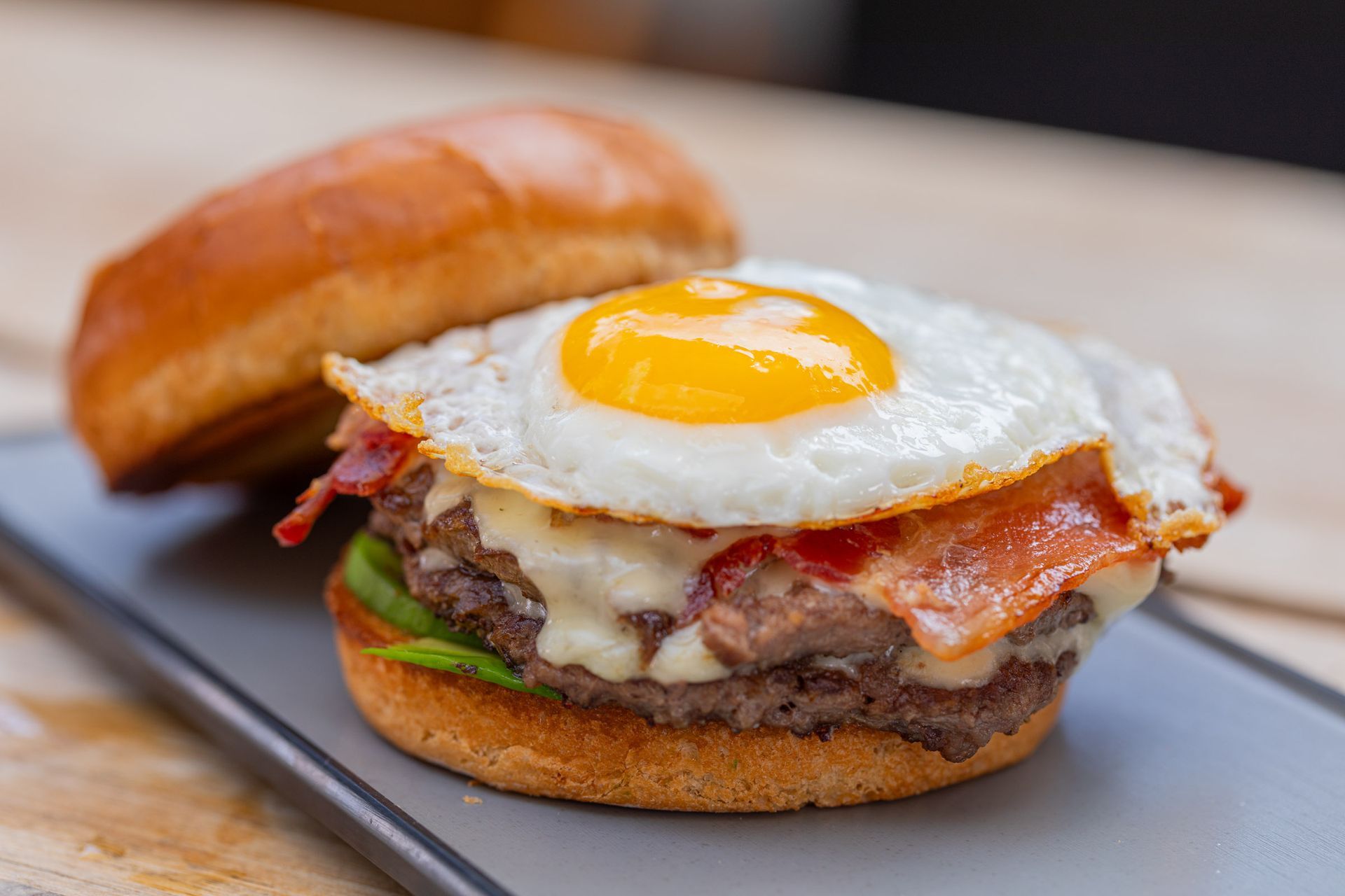 A hamburger with lettuce and cheese on a bun on a metal tray.
