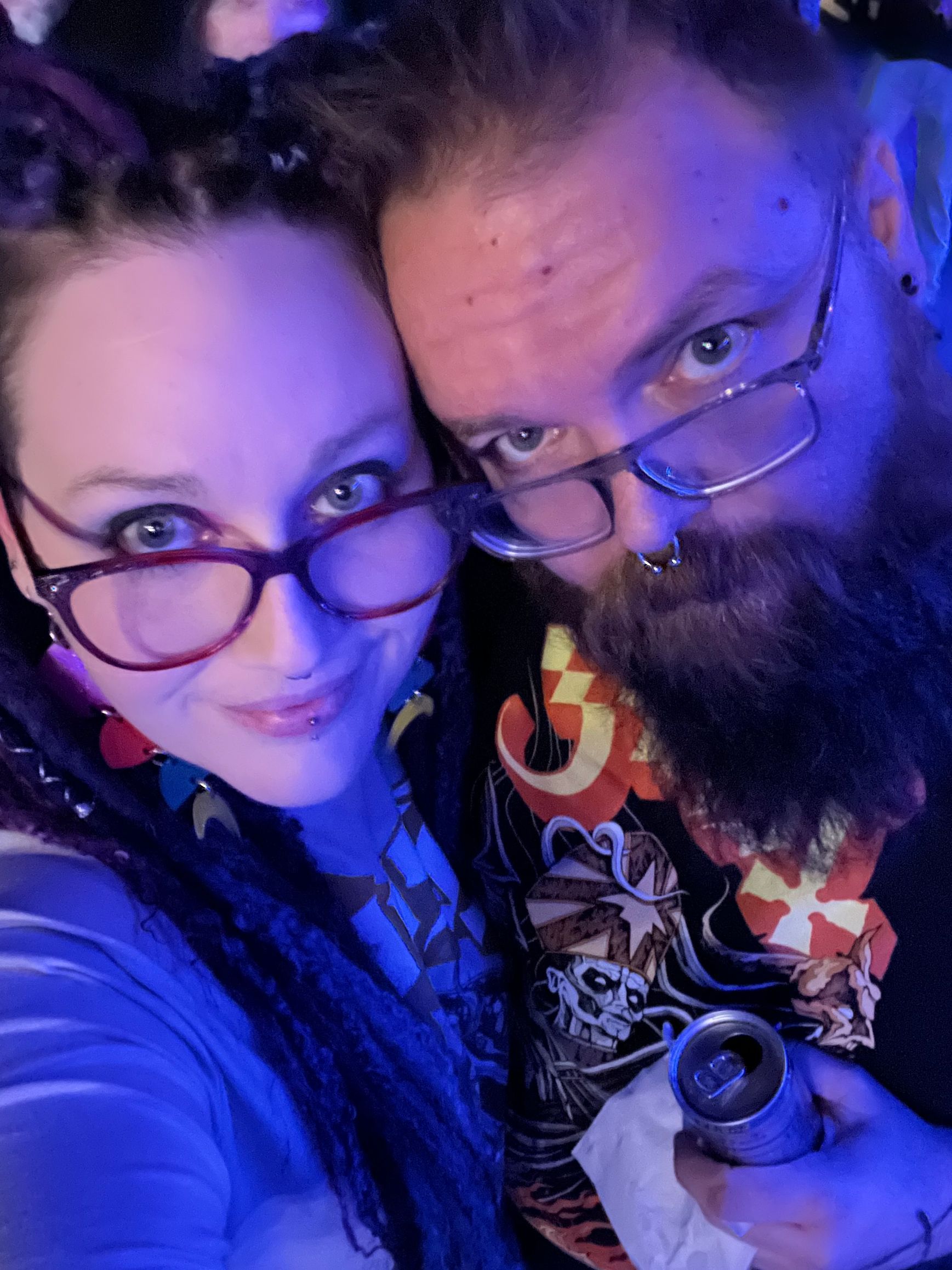 A man and a woman are posing for a picture while the man is holding a can of beer.