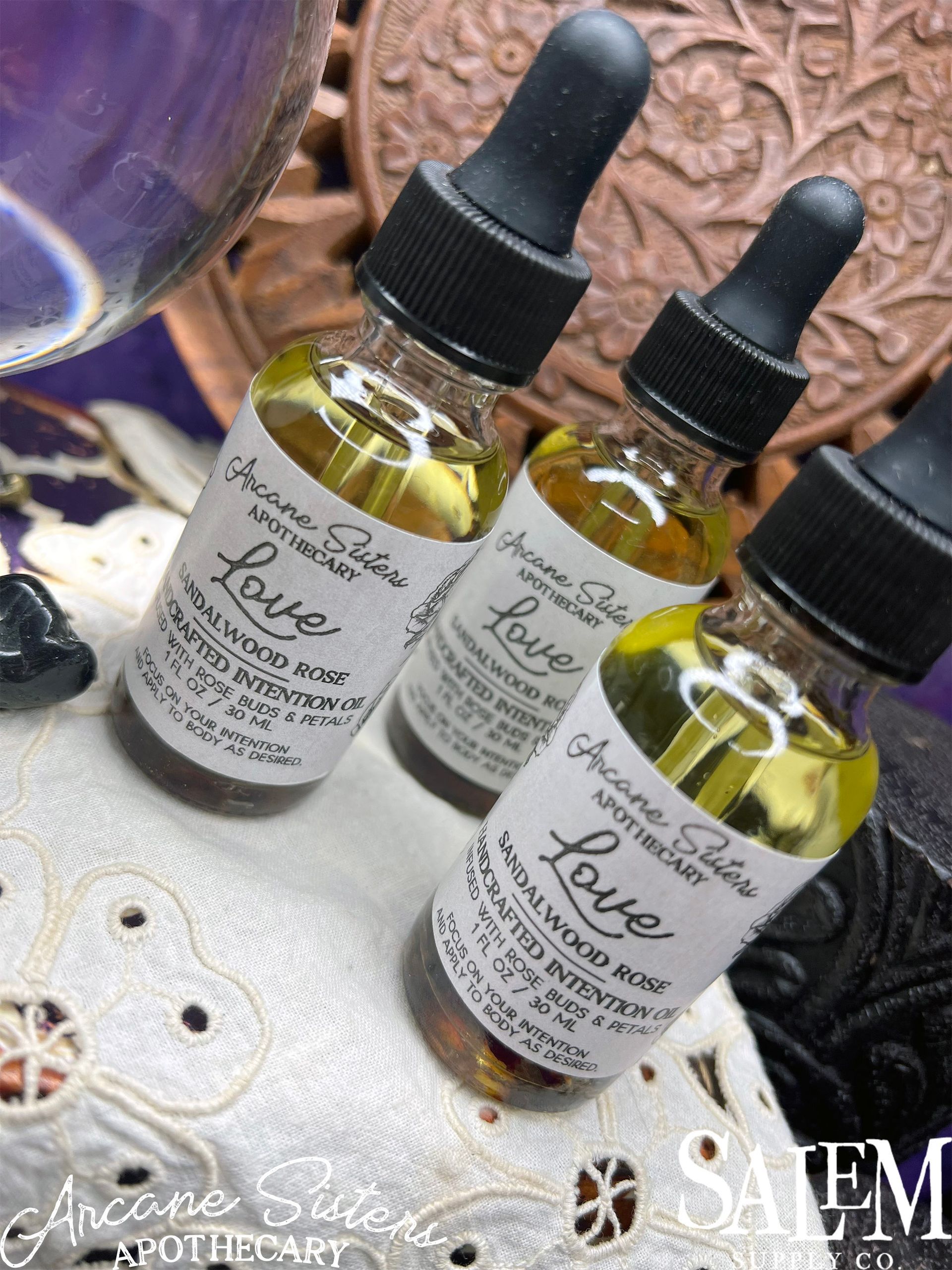 Three bottles of love oil are sitting on a table.