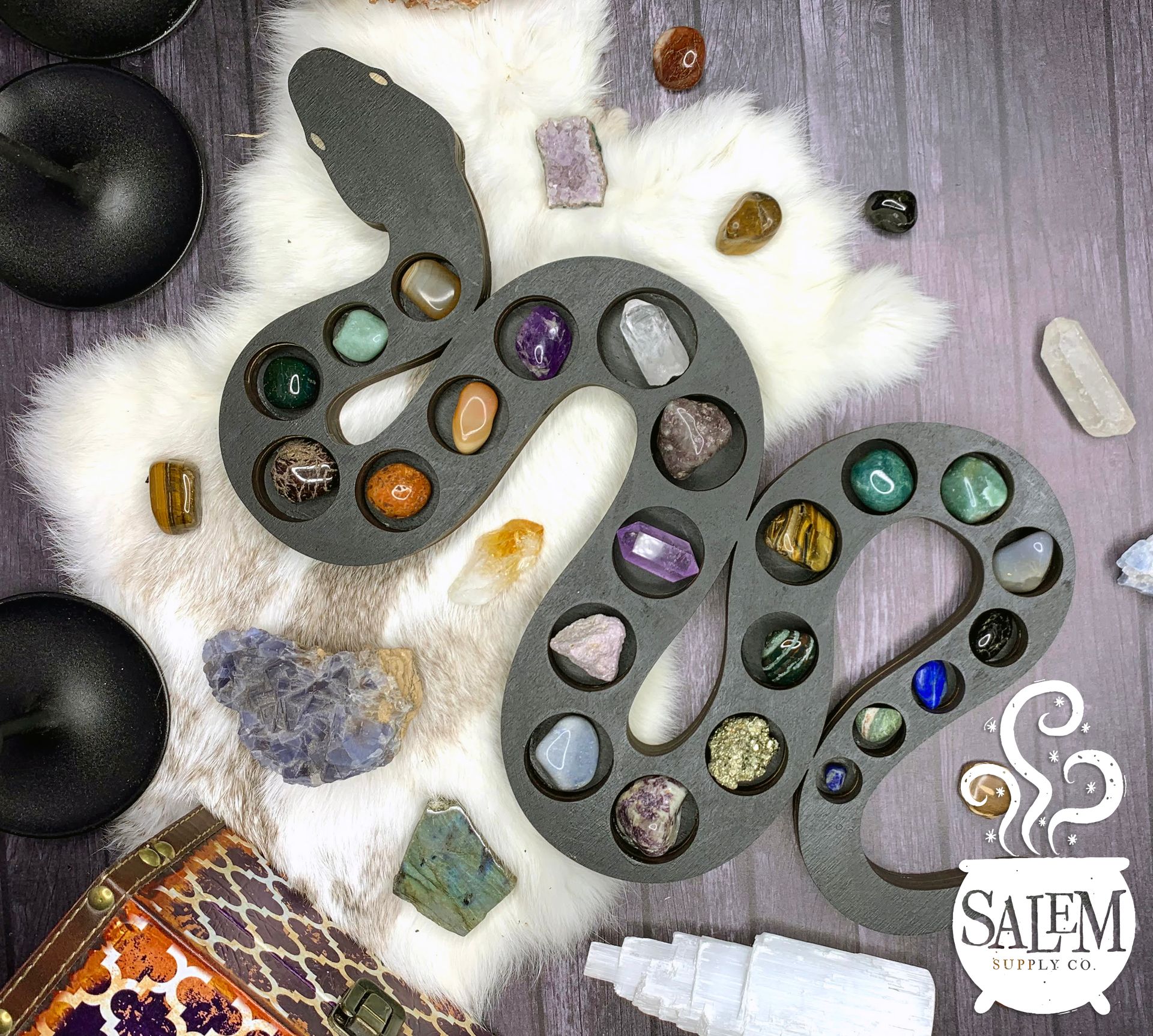 A snake shaped tray filled with crystals on a wooden table.