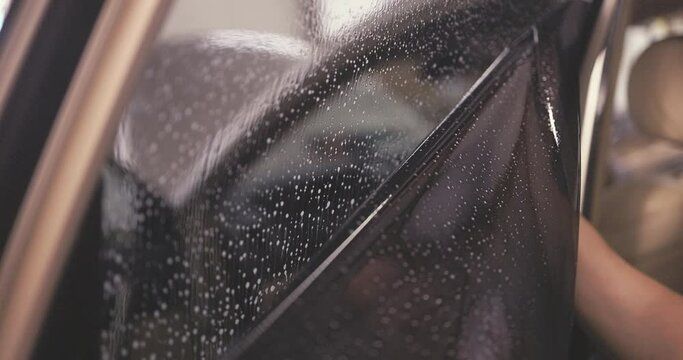 A close up of a person cleaning a car window with a wiper.