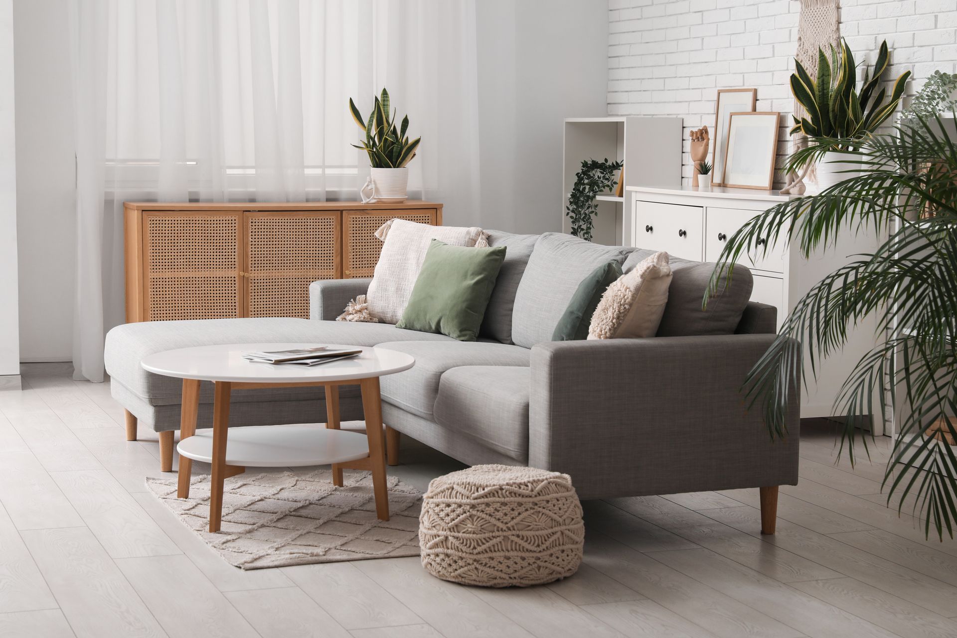 Living room with gray sectional sofa, coffee table, and plants.