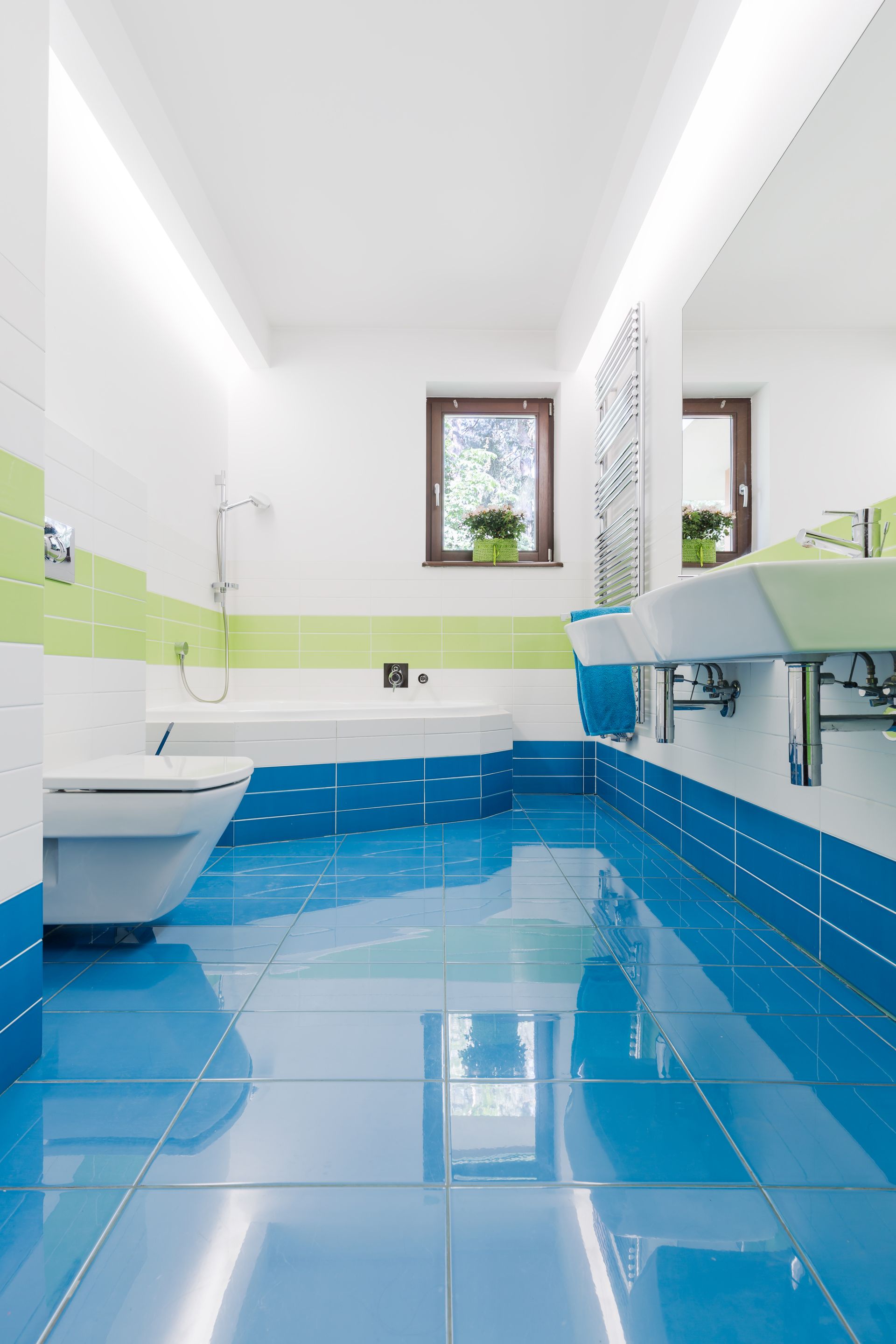 Modern bathroom with bright blue tiled floor and baseboards, white walls with lime green accents, and white fixtures.