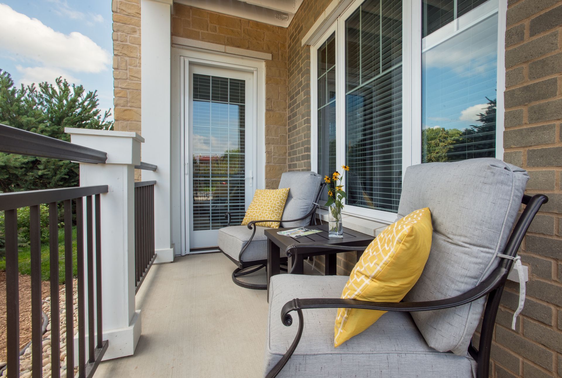 There are two chairs and a table on the balcony.