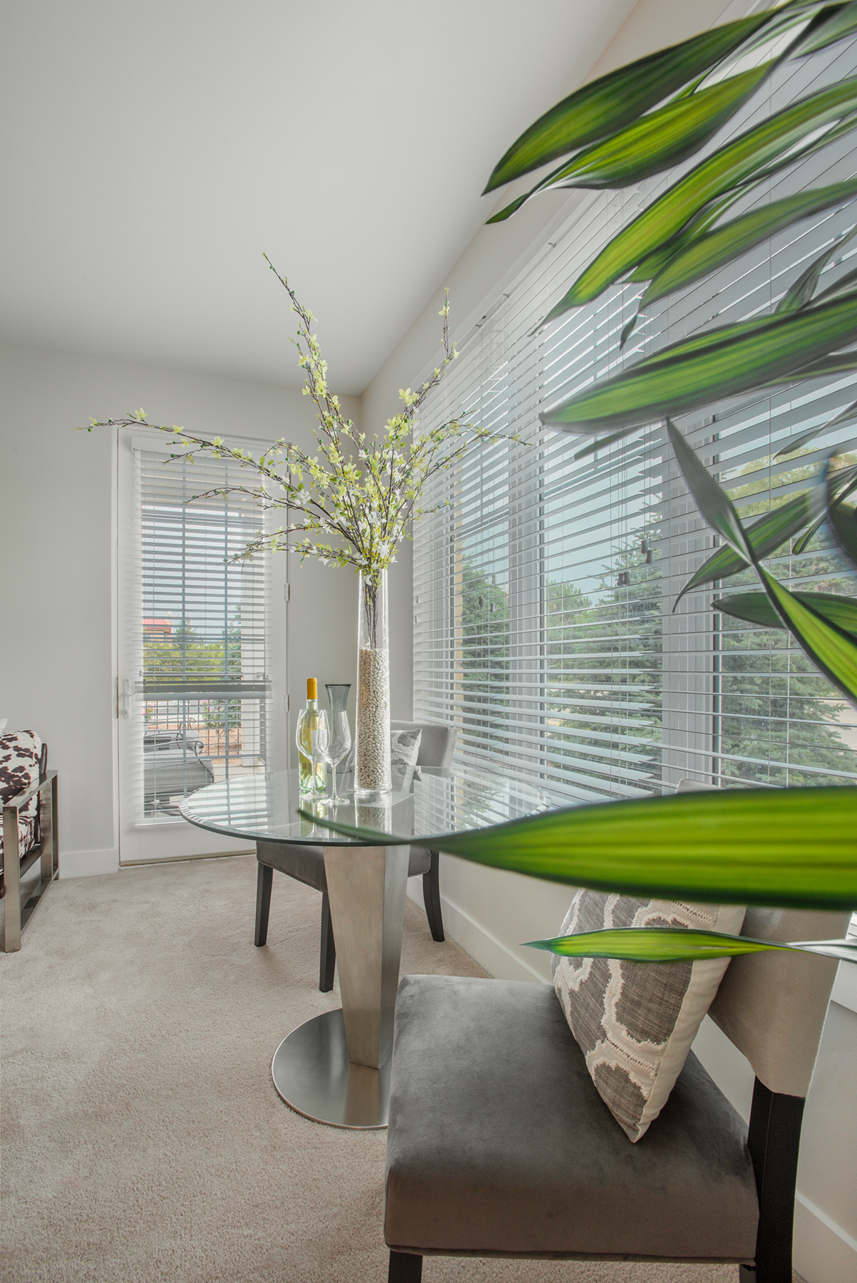 A living room with a dining table and chairs and a window with blinds.