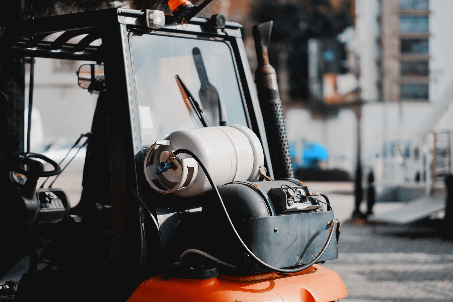 Orange forklift with propane tank, parked outdoors.