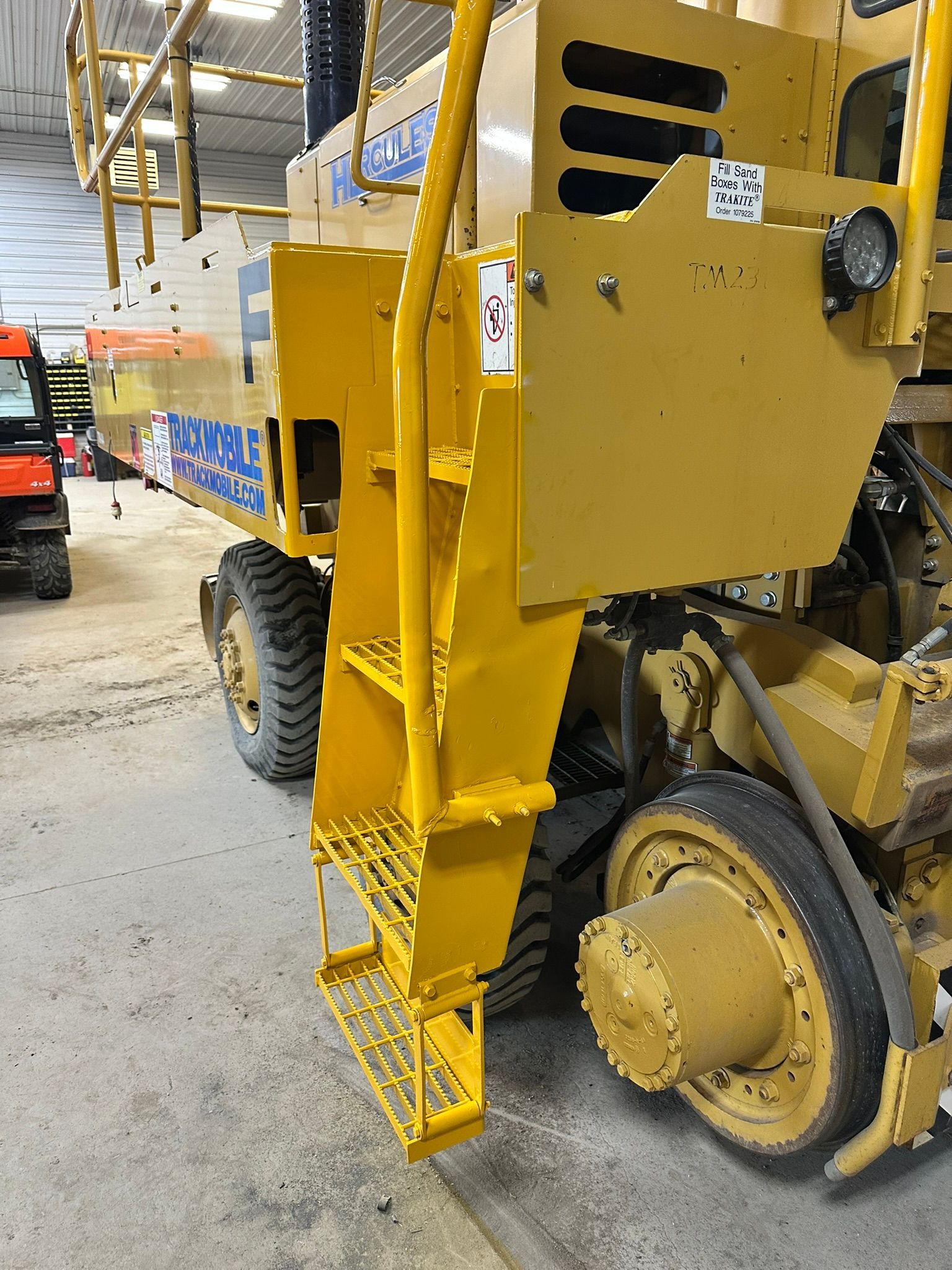 Yellow industrial vehicle with ladder and tires.