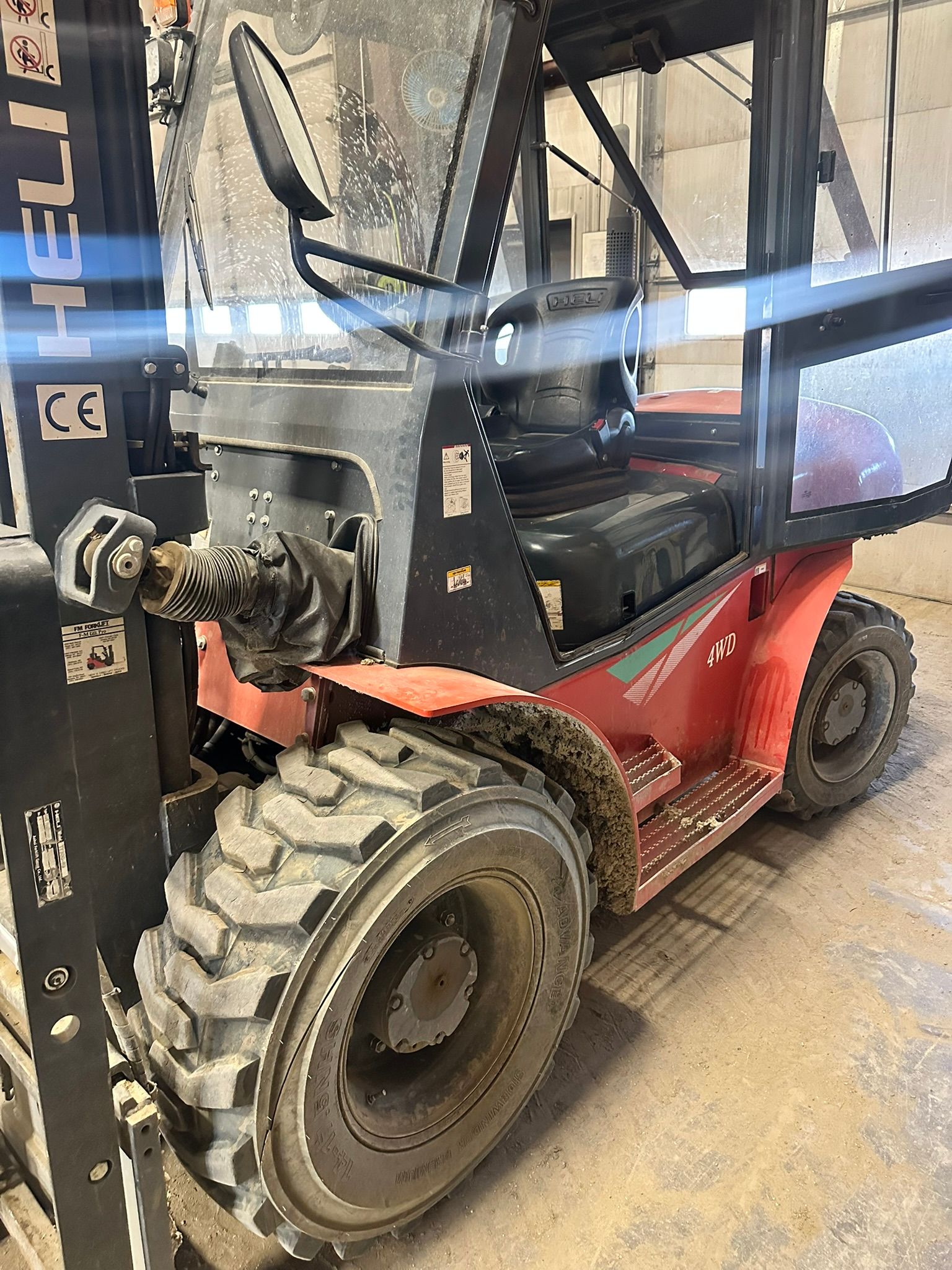Red forklift with black details, tires, and cab, in an indoor setting.