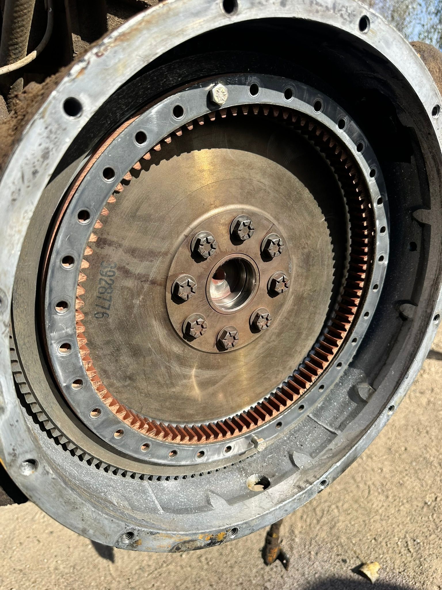 Close-up of a large circular metal component with a toothed ring. Rust and bolts are visible.