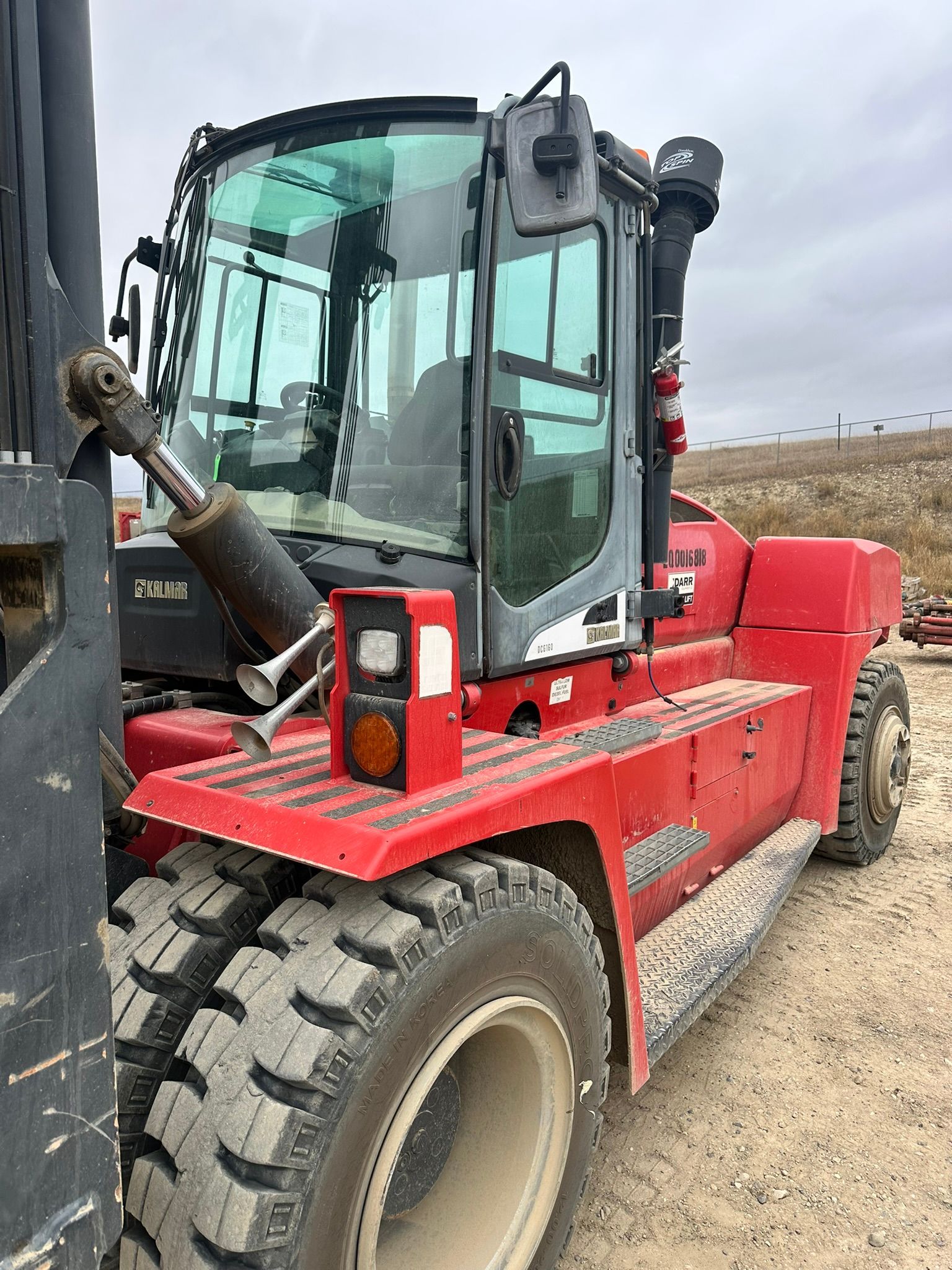 Red Kalmar forklift with a raised cab and large tires, parked outdoors.