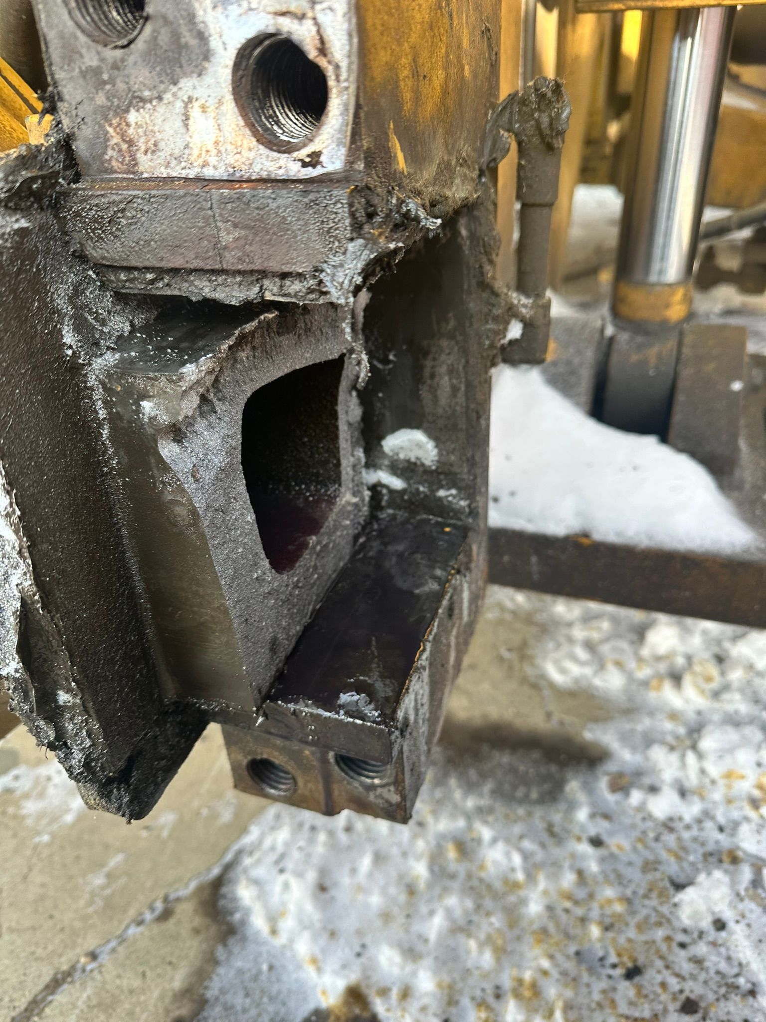 Close-up of a damaged metal machine part with a hollow section, covered in grime and residue.
