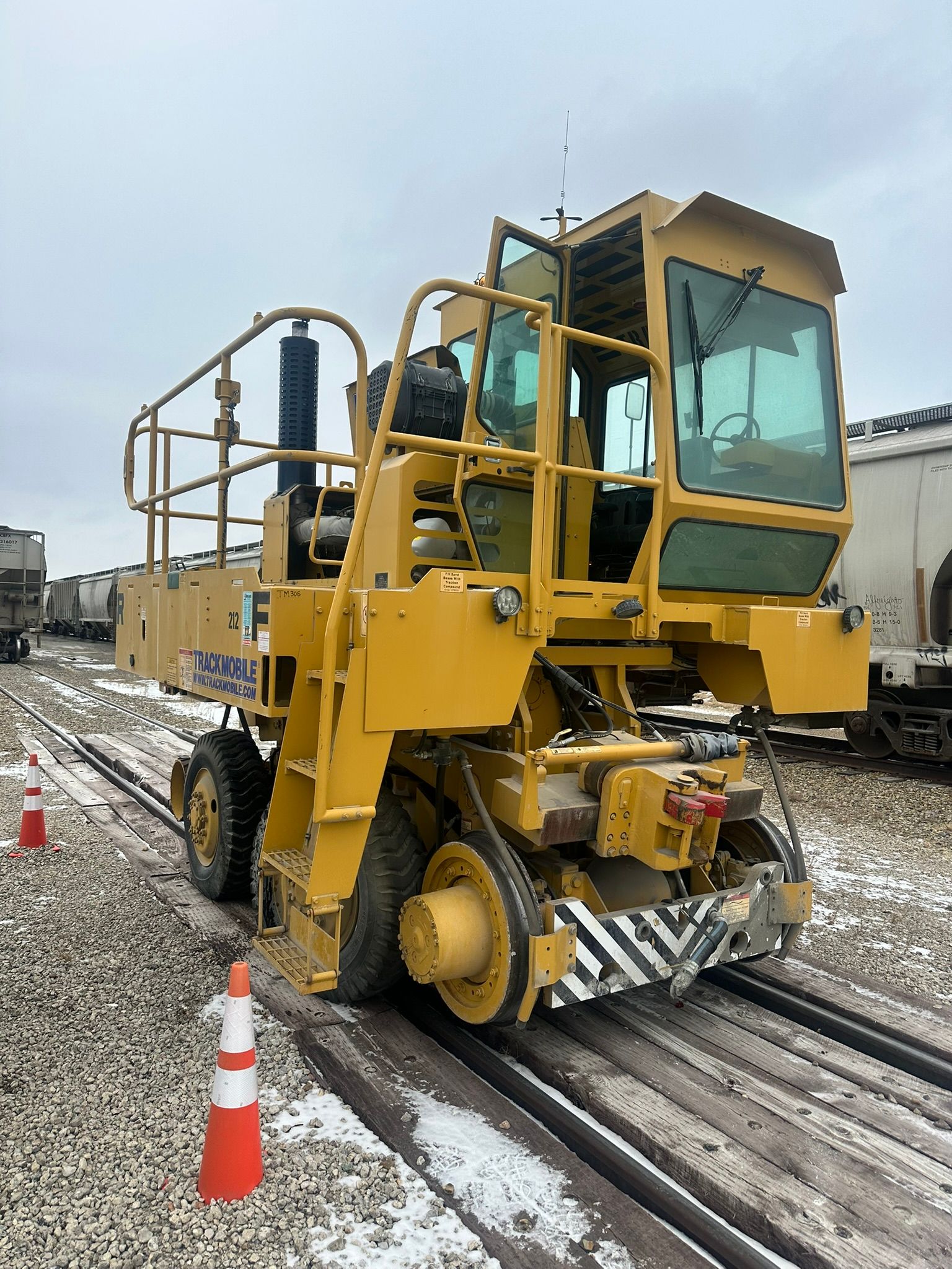 Yellow railcar on tracks with orange traffic cones.