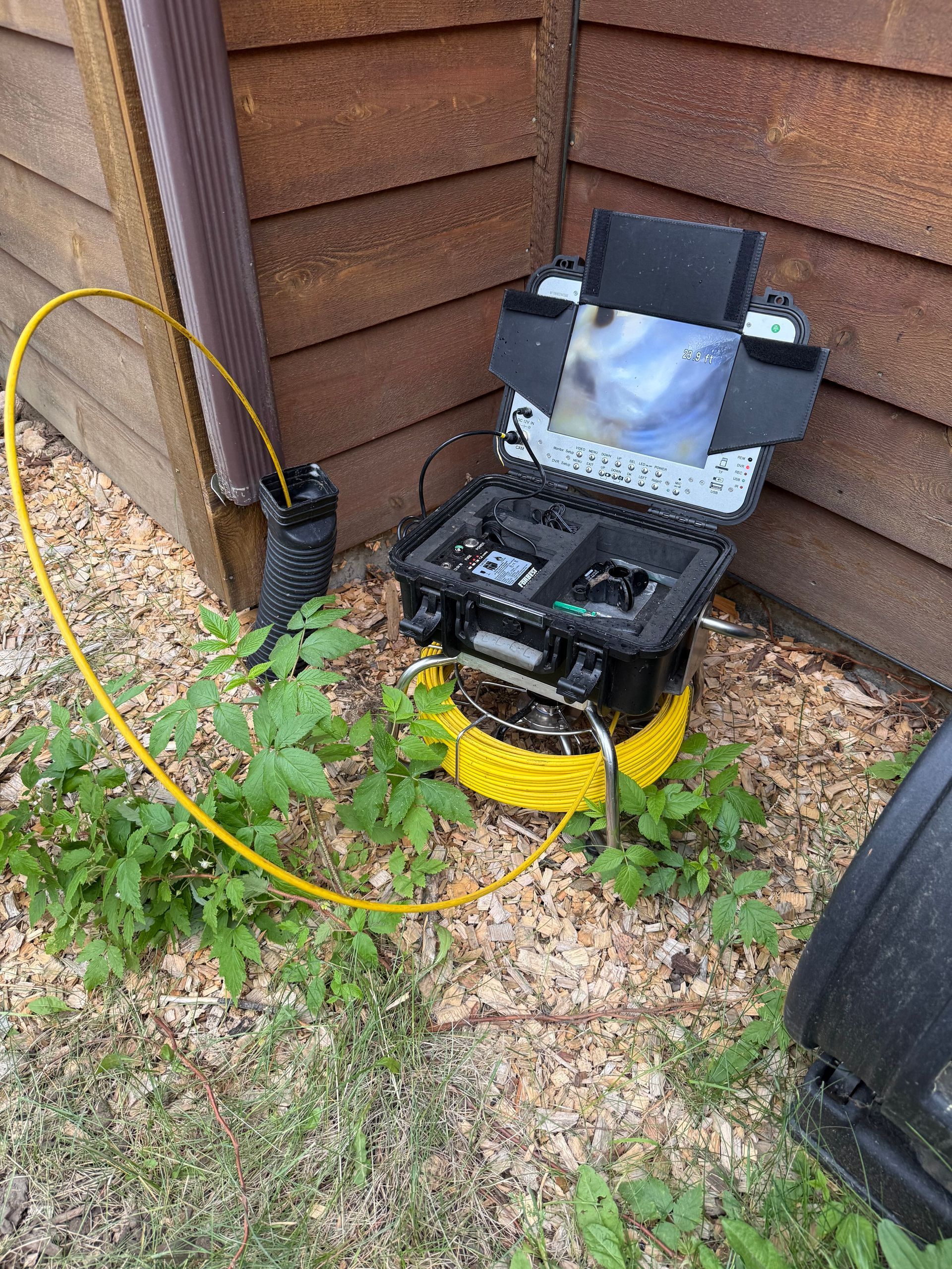 A camera is sitting on the ground next to a wooden wall.