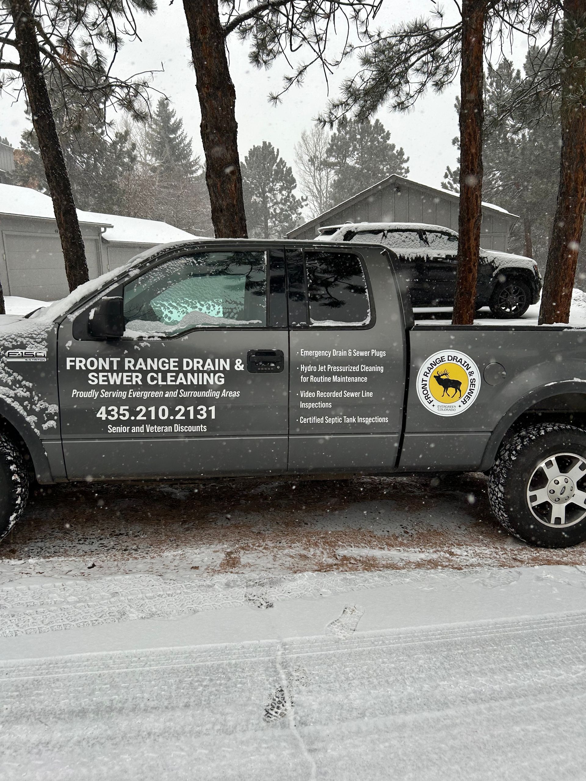 A truck is parked in the snow in front of a house.