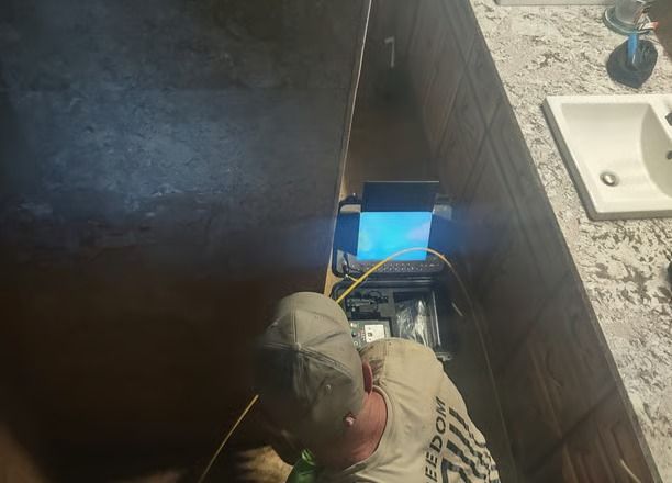 A man is working on a computer in a bathroom.