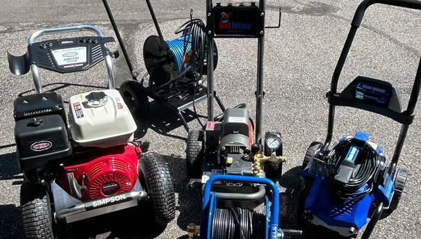 A group of pressure washers are sitting next to each other on the ground.