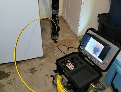 A camera is being used to look at a pipe in a basement.