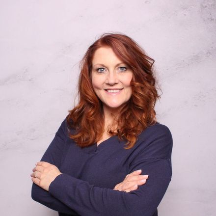 a woman with red hair is smiling with her arms crossed