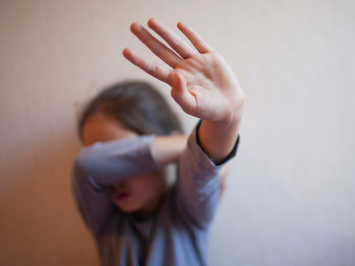 a young girl is covering her face with her hand .