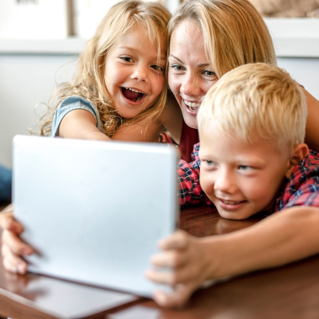 A Courageous Voice / A mother and her daughter and son around a tablet, smiling and laughing. 