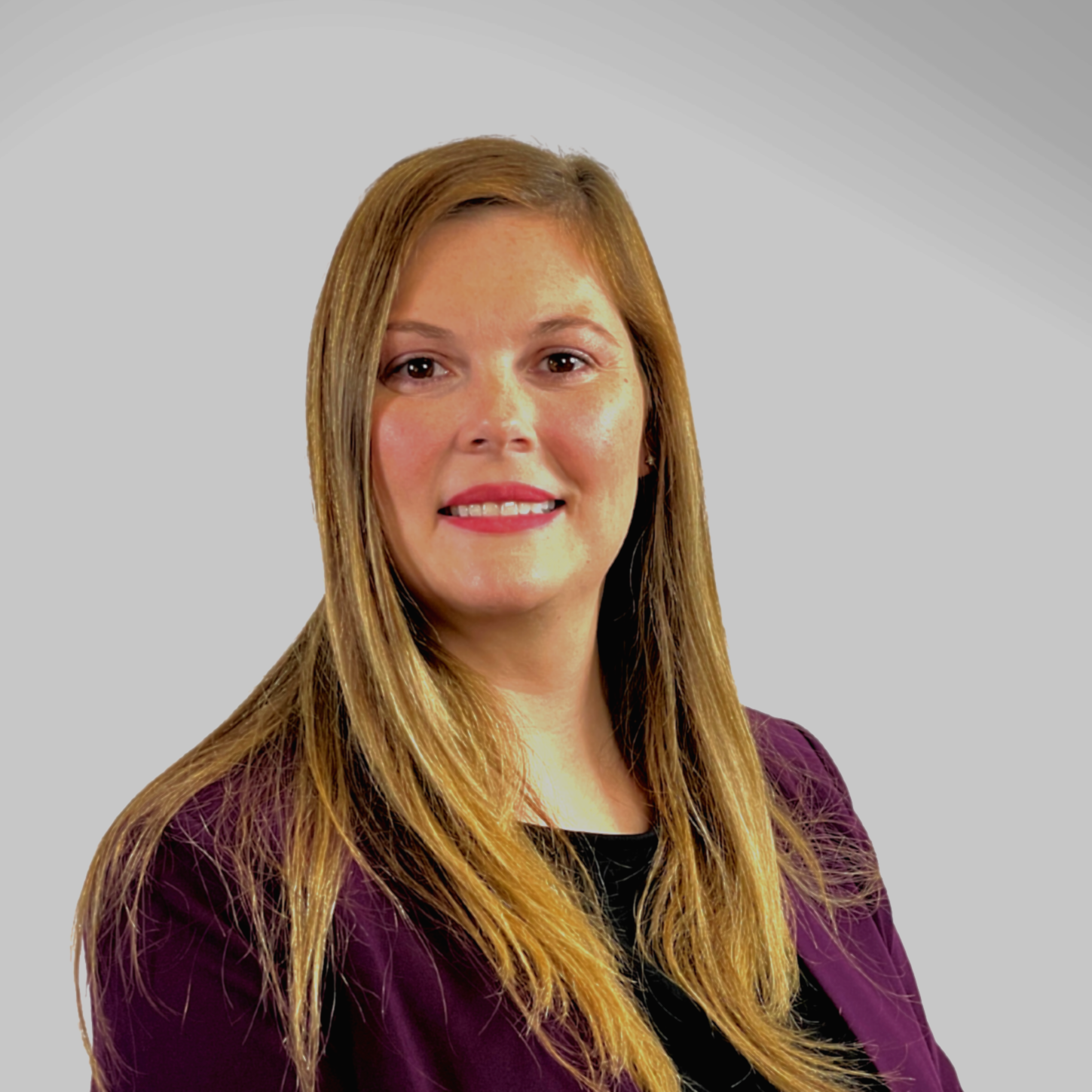 A woman with long blonde hair is wearing a purple jacket and smiling.