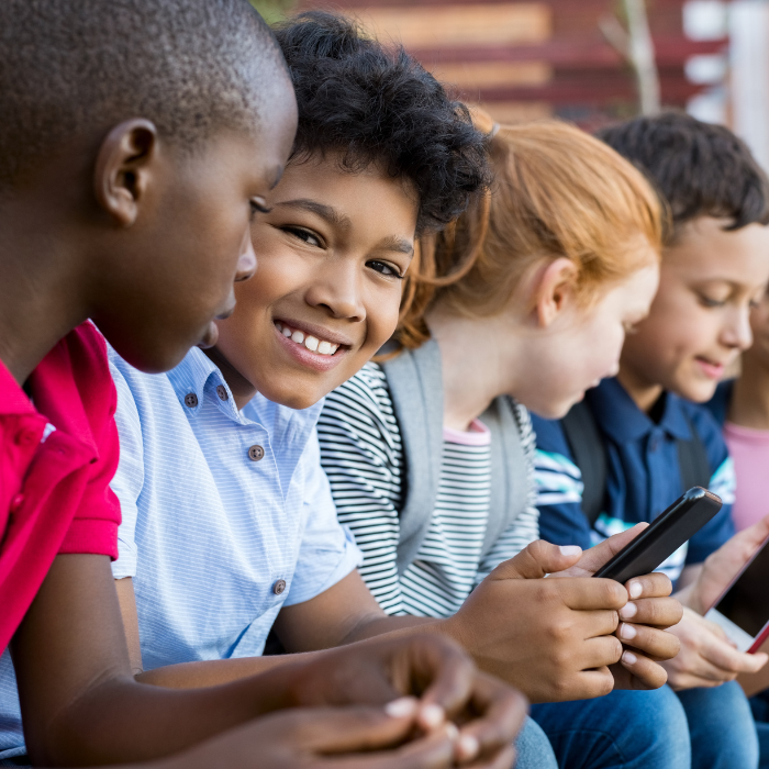 a group of children are looking at their cell phones