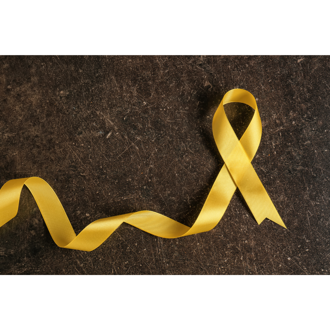 A yellow ribbon, a symbol of suicide awareness, against a dark cement background.