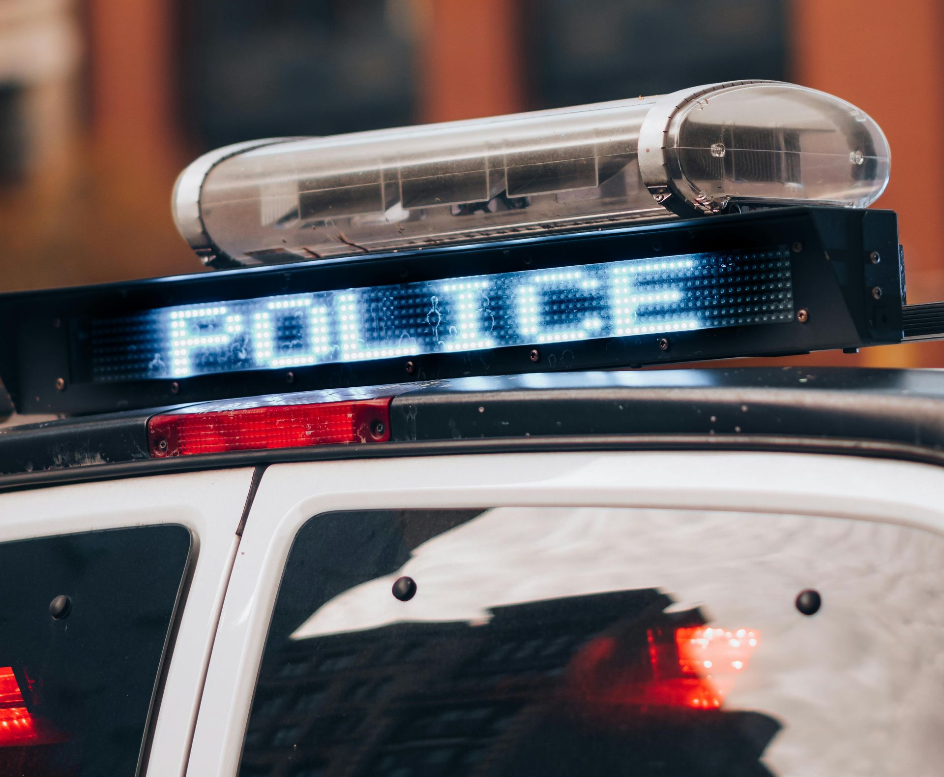 Police car roof light bar flashing blue and red, with POLICE sign visible