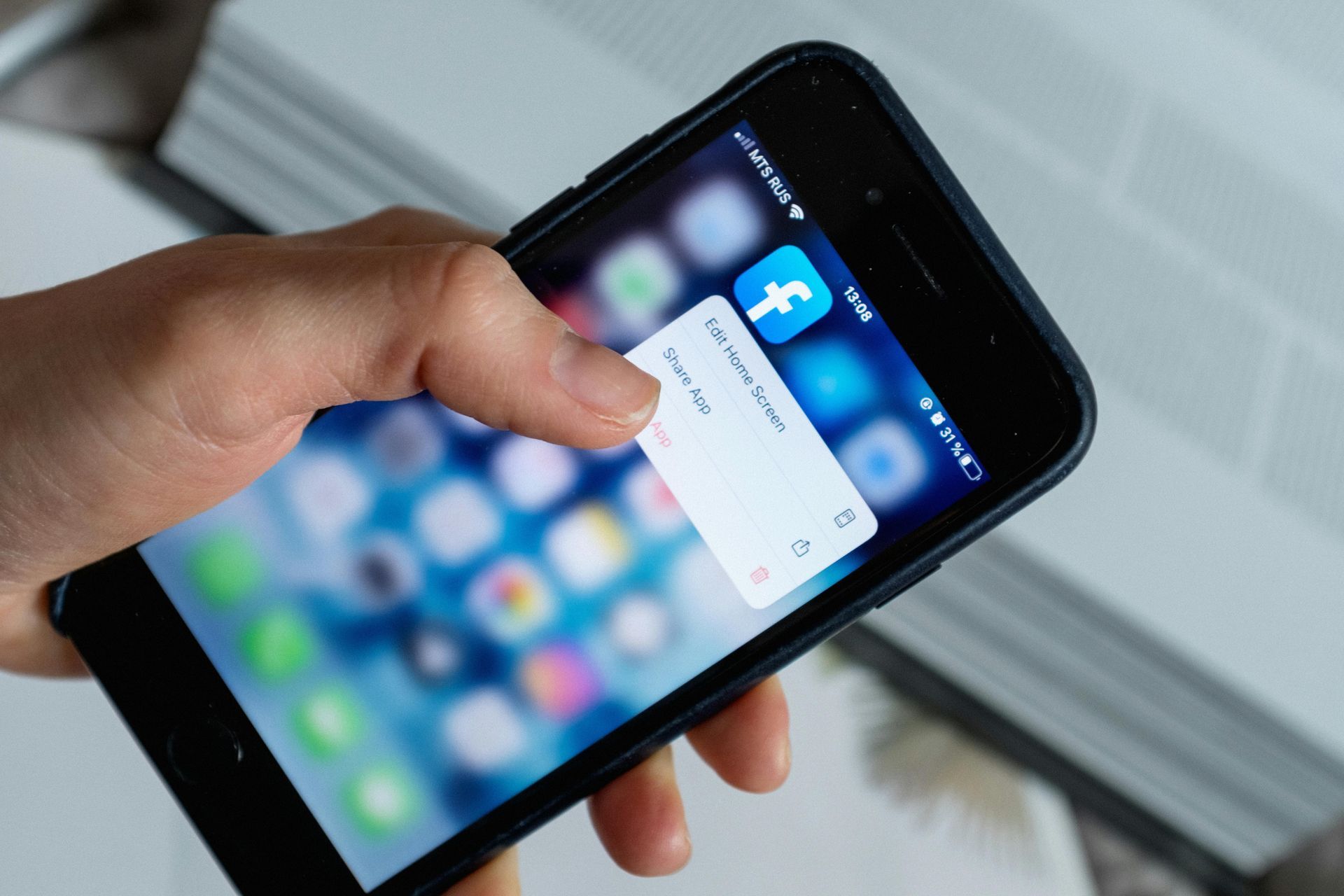 Hand holding a smartphone with a Facebook login pop-up on the screen