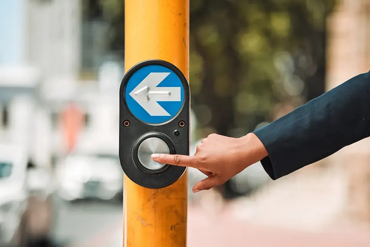 Finger on a crosswalk button.