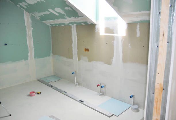A bathroom is being remodeled with drywall and a level on the floor.