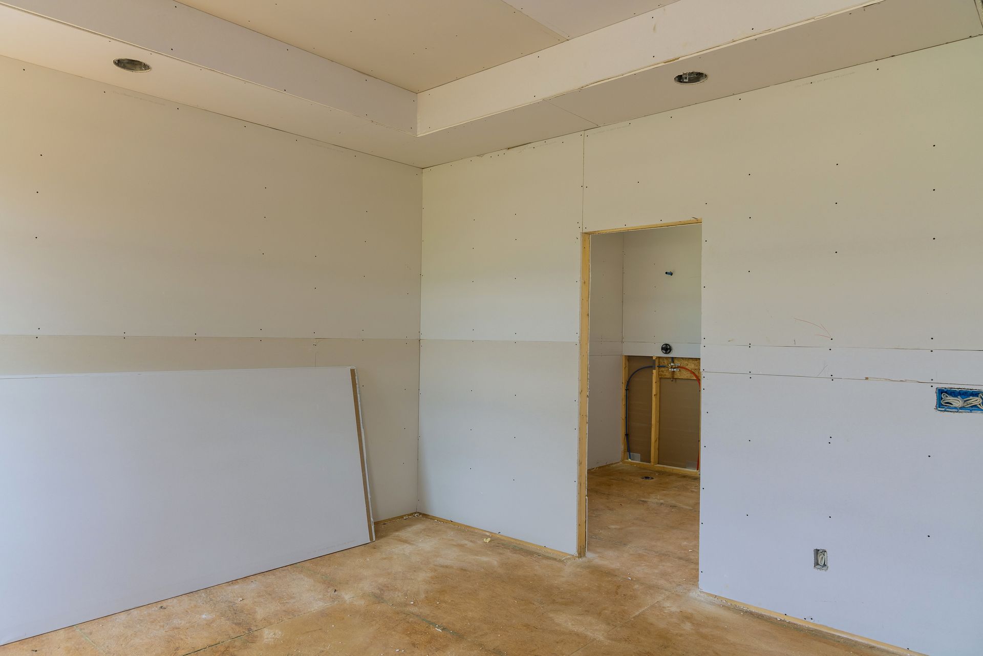An empty room with white walls and a wooden floor in a house under construction.